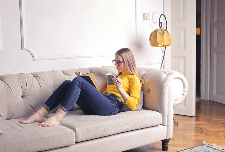 woman-sitting-on-white-couch-while-reading-a-book