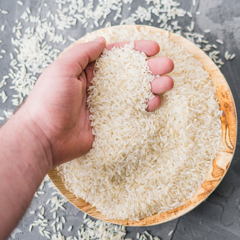 close-up-white-uncooked-rice-human-hand-wooden-plate-768