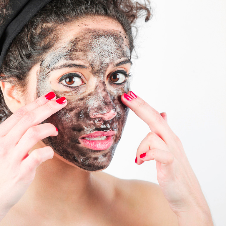 close-up-young-woman-applying-black-face-mask-with-her-fingers-768