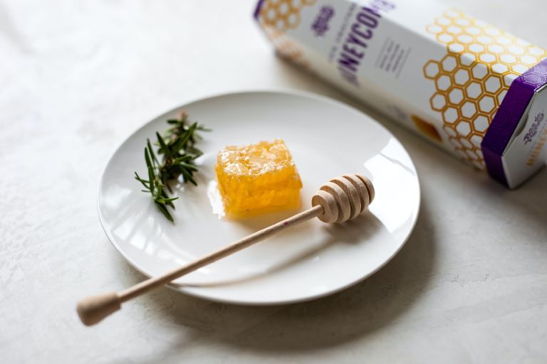raw honeycomb on a white plate with rosemary
