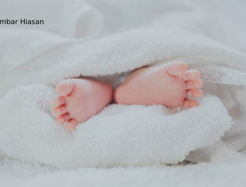 barefooted baby covering white blanket