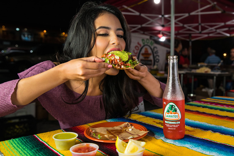 A-woman-eats-a-tostada-at-a-street-taco-stand-in-Los-Angeles-at-night
